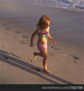 Six year old girl running on the beach