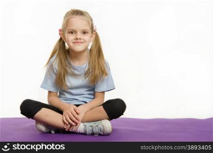 Six year old girl sitting on the mat for practice. Six year old girl Europeans engaged in physical exercises