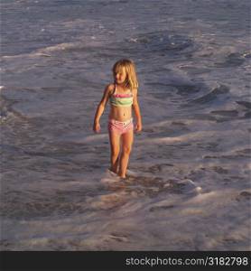 Six year old girl walking in the ocean
