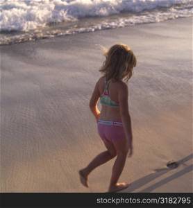 Six year old girl walking on the beach