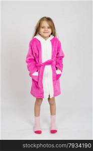 Six year old girl with wet hair in a bathrobe on a light background. Portrait of a six-year growth girl in bathrobe