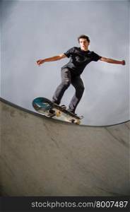 Skateboarder doing a grind on a croncrete pool at the skate park.