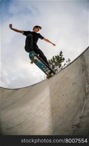 Skateboarder doing a tail slide on a croncrete pool at the skate park.