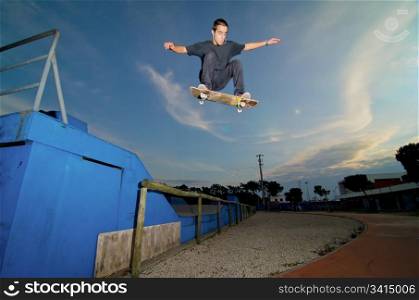 Skateboarder flying over a ramp on sunset at the local skatepark.