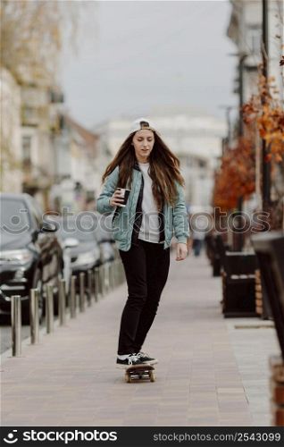 skateboarder girl holding cup coffee while riding skate