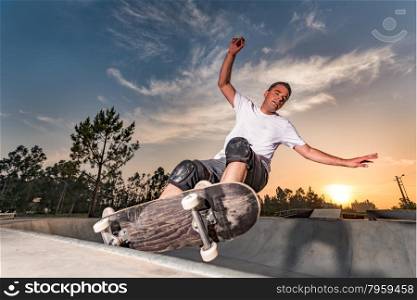 Skateboarder in a concrete pool at skatepark on a beatiful sunset.