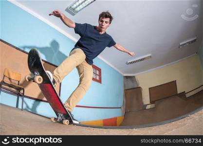 Skateboarder performing a blunt to fakie on a mini ramp at indoor skate park.