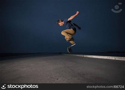 Skateboarder performing a ollie flip on a concrete pavement along the harbour.