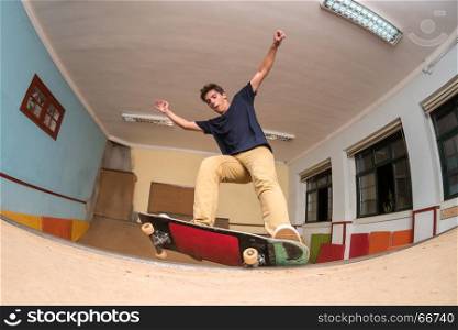Skateboarder performing a trick on mini ramp at indoor skate park.