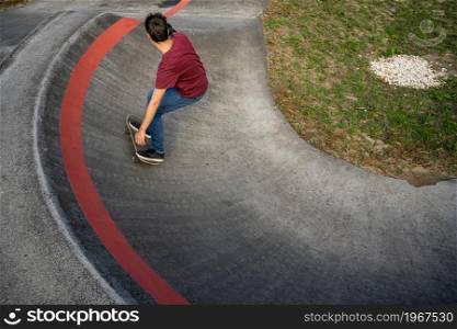 Skateboarder practice on a pump track park on a sunny day.