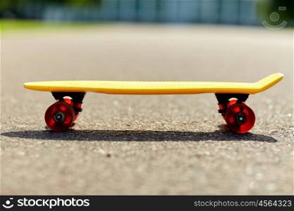 skateboarding, leisure, extreme sport and equipment concept - close up of short modern cruiser skateboard on road