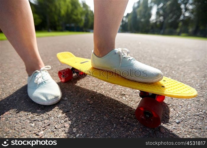 skateboarding, leisure, extreme sport and people concept - close up of teenage girl legs riding short modern cruiser skateboard on road. close up of female feet riding short skateboard