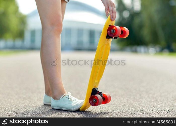 skateboarding, leisure, extreme sport and people concept - close up of teenage girl legs with short modern cruiser skateboard on road