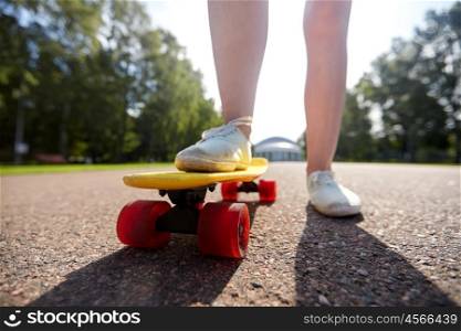 skateboarding, leisure, extreme sport and people concept - close up of teenage girl legs riding short modern cruiser skateboard on road