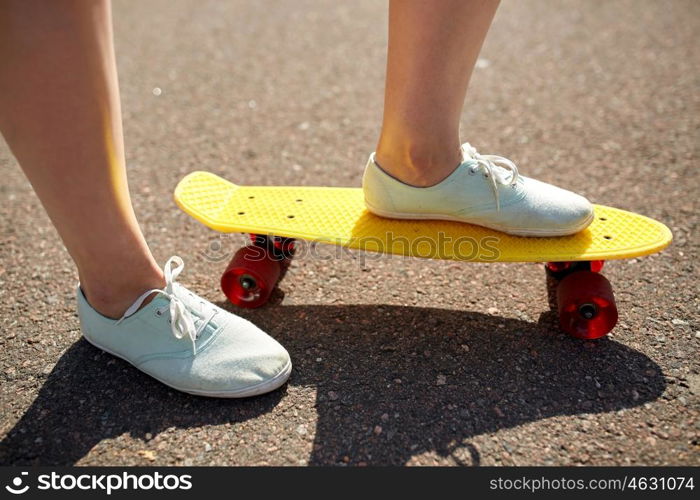 skateboarding, leisure, extreme sport and people concept - close up of teenage girl legs riding short modern cruiser skateboard on road