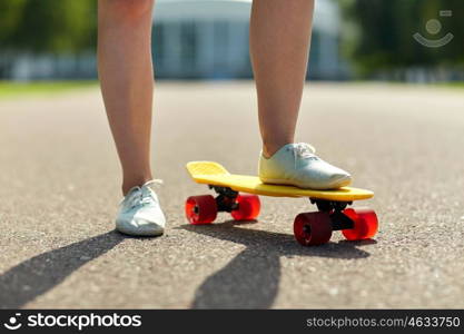 skateboarding, leisure, extreme sport and people concept - close up of teenage girl legs riding short modern cruiser skateboard on road