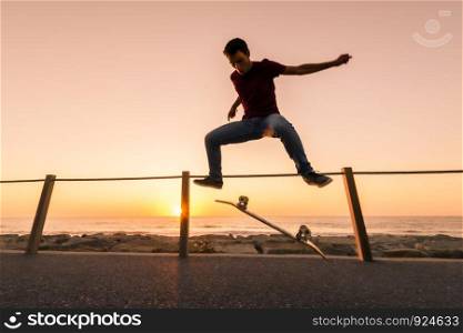 Skater make trick kickflip against the beautiful orange sunset.
