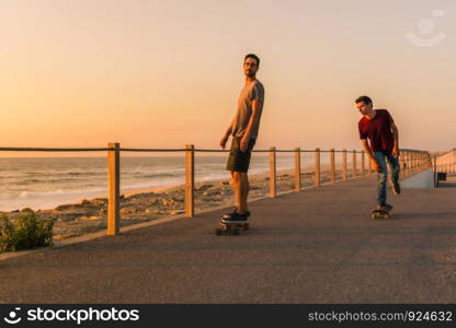 Skaters training in the park near the sea in sunset.