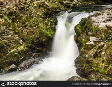 Skelwith Falls waterfall with green moss in slow motion shot in Lake District