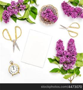 Sketchbook, lilac flowers, office tools and golden accessories. Flat lay spring blossoms