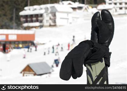 Ski gloves and sticks. Winter tourists on the background.