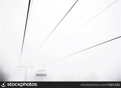 Ski lift in a dense morning fog