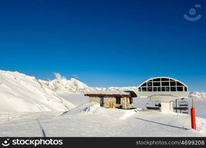 Ski lift station in mountains at winter. Alpine winter mountain landscape. French Alps covered with snow in sunny day. Val-d'Isere, Alps, France