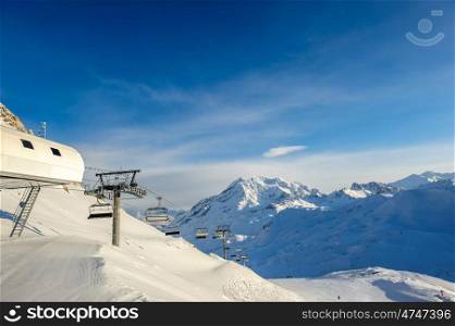 Ski lift station in mountains at winter. Alpine winter mountain landscape. French Alps covered with snow in sunny day. Val-d'Isere, Alps, France