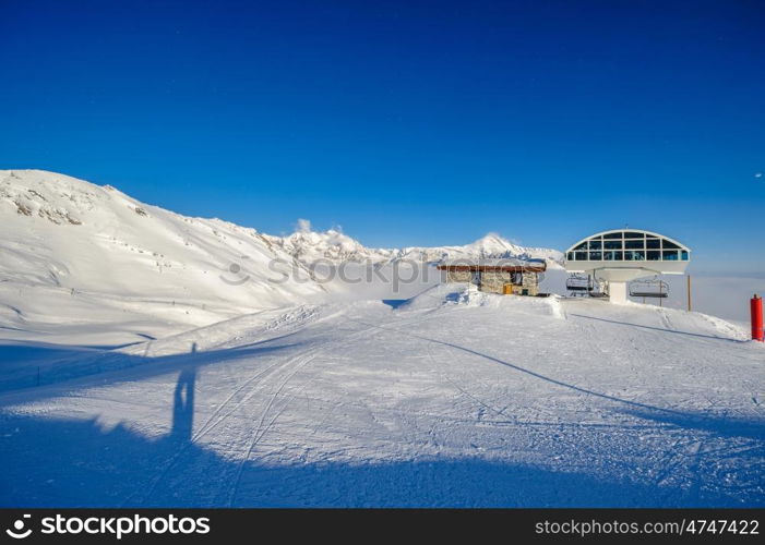 Ski lift station in mountains at winter. Alpine winter mountain landscape. French Alps covered with snow in sunny day. Val-d'Isere, Alps, France