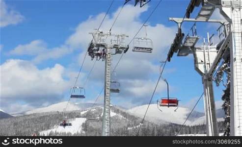 ski lifts with skiers are moving over snow-covered mountains, bottom view