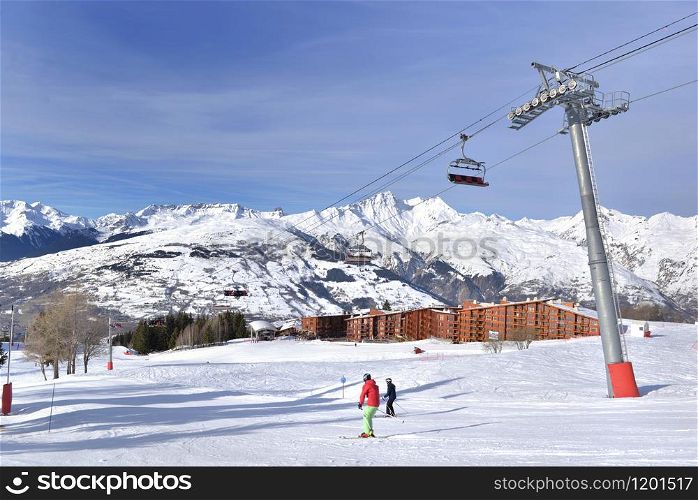 ski slopes in french alps resort and chair lift under blue sky