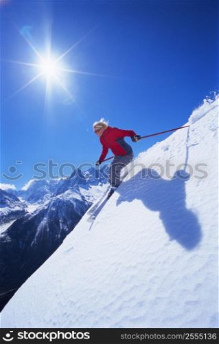 Skier coming down snowy hill smiling (lens flare)