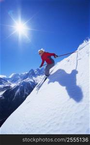 Skier coming down snowy hill smiling (lens flare)