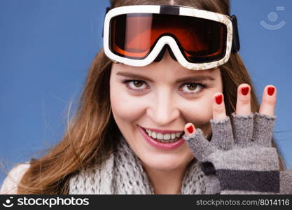 skier girl wearing warm clothes ski googles portrait. . Woman skier girl wearing warm clothing ski googles portrait. Winter sport activity. Beautiful sportswoman showing gloves and red nails manicure on blue studio shot