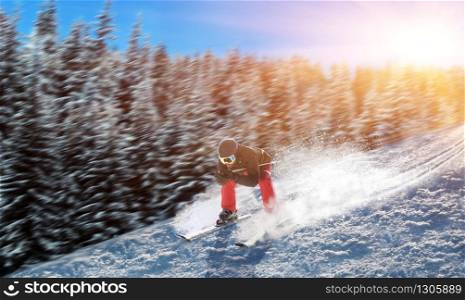 Skier in helmet and glasses racing from the mountain. Winter active sport, extreme lifestyle. Downhill skiing
