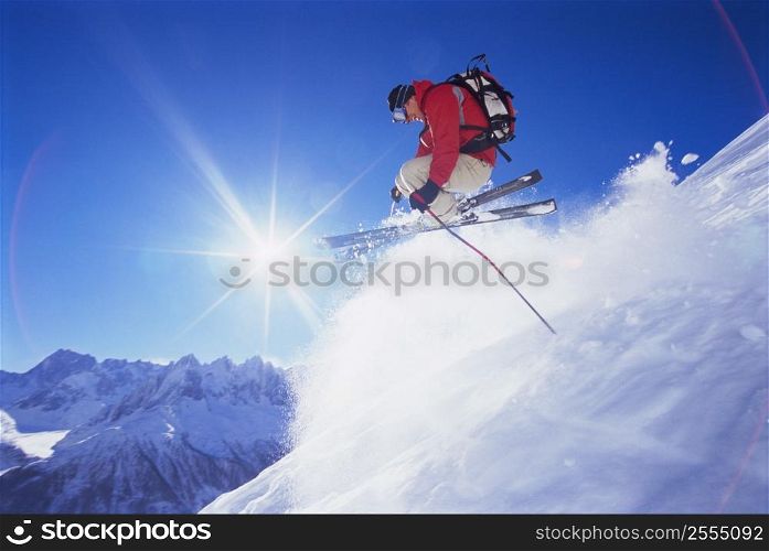 Skier jumping on snowy hill (lens flare)