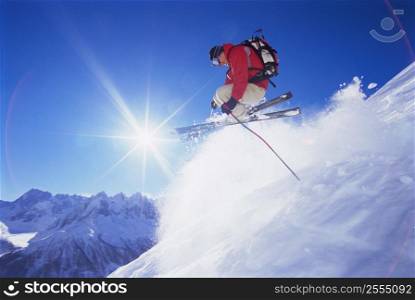 Skier jumping on snowy hill (lens flare)