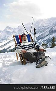 Skier resting in deckchair in mountains
