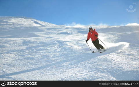 skier skiing downhill on fresh powder snow with sun and mountains in background