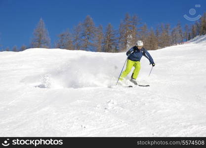 skier skiing downhill on fresh powder snow with sun and mountains in background