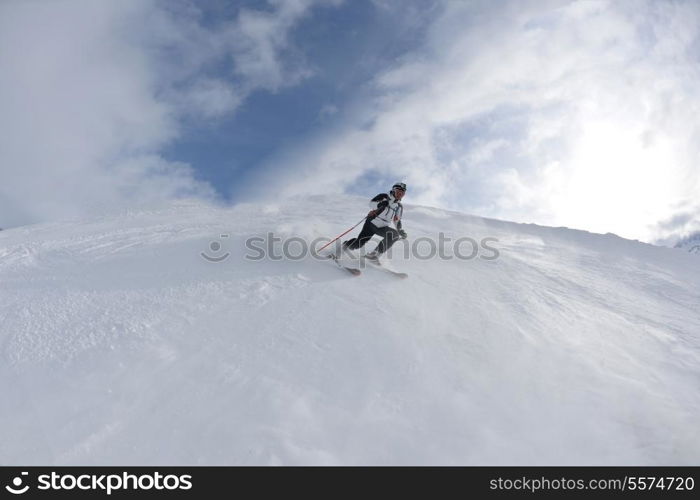 skier skiing downhill on fresh powder snow with sun and mountains in background