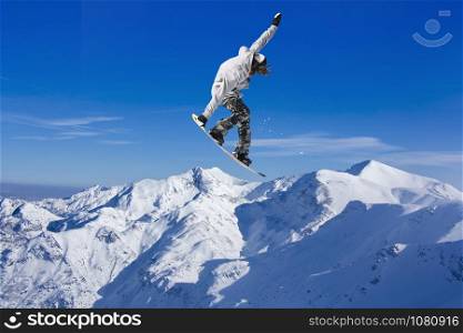 Skier Snowboarder jumping through air with blue sky in background