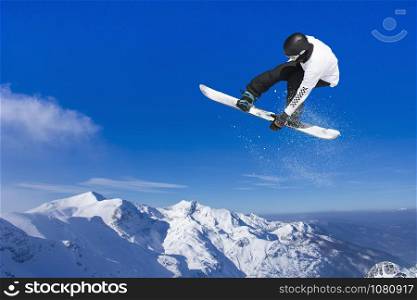 Skier Snowboarder jumping through air with blue sky in background