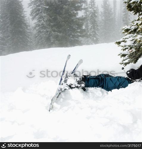 Skiers lying in snow near tree after crash in fog.
