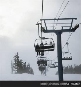 Skiers riding the chairlift in foggy winter weather.