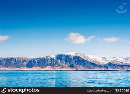 Skies over a mountain with snow by the blue sea in Iceland