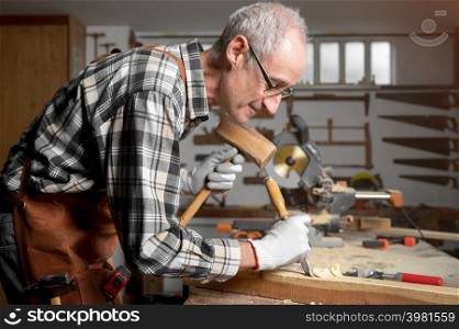 Skilled carpenter carving wood with hammer and chisel. High quality photography. Skilled carpenter carving wood with hammer and chisel