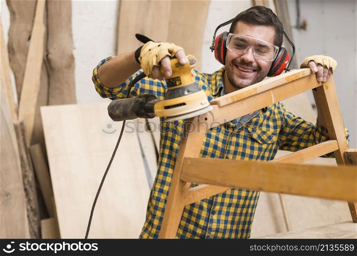 skilled carpenter is using power sander as tool polish his furniture