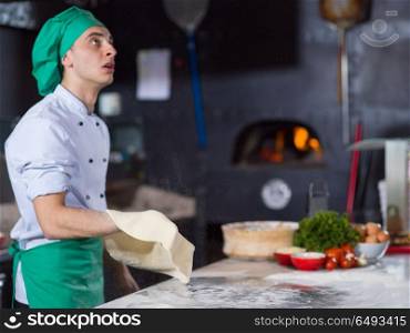 Skilled chef preparing dough for pizza rolling with hands and throwing up. chef throwing up pizza dough