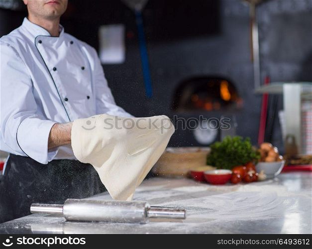 Skilled chef preparing dough for pizza rolling with hands and throwing up. chef throwing up pizza dough